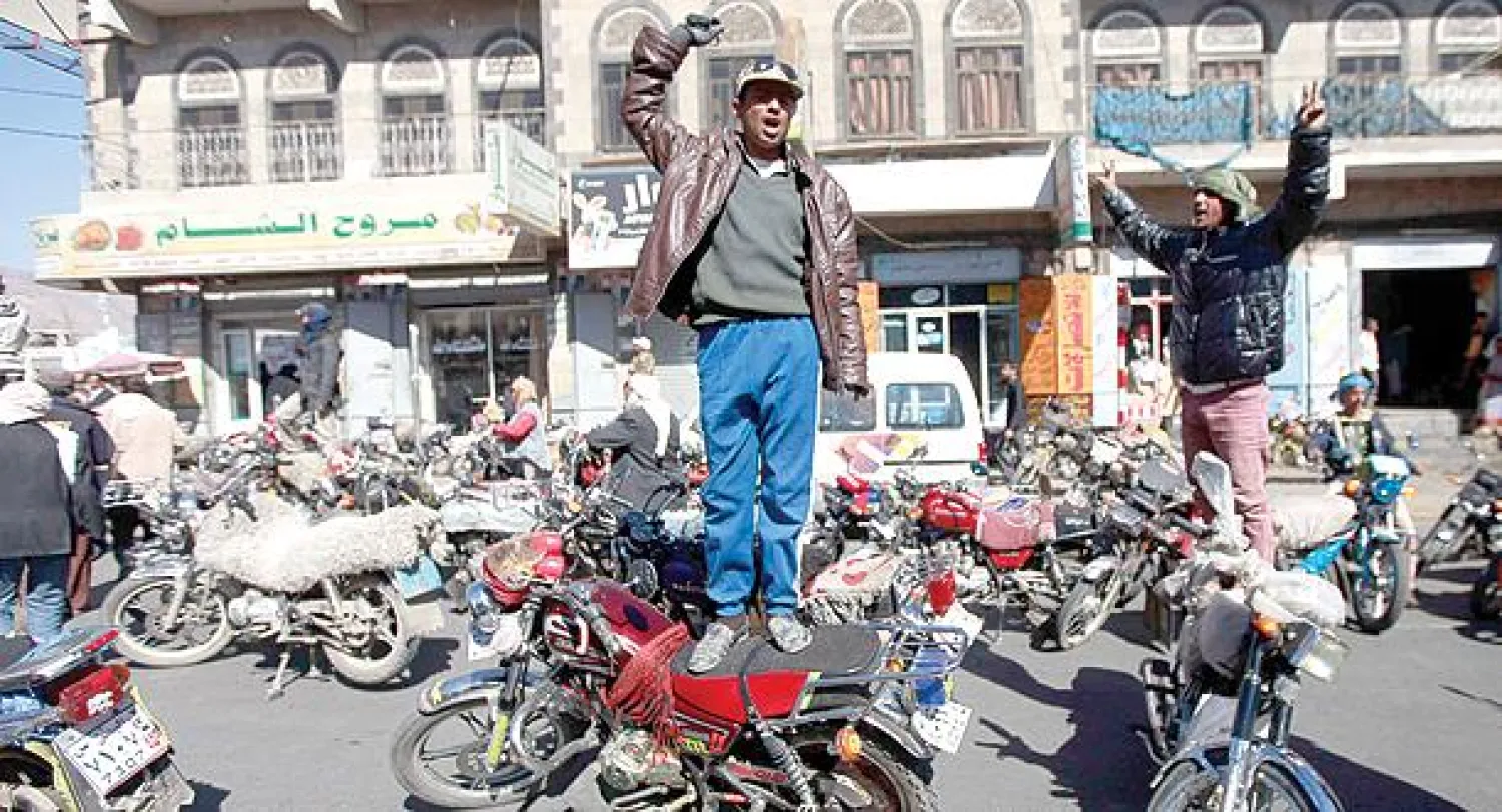 متظاهران يمنيان يقفان فوق عشرات من الدراجات النارية  تنديدا بحظرها في صنعاء أمس (رويترز)