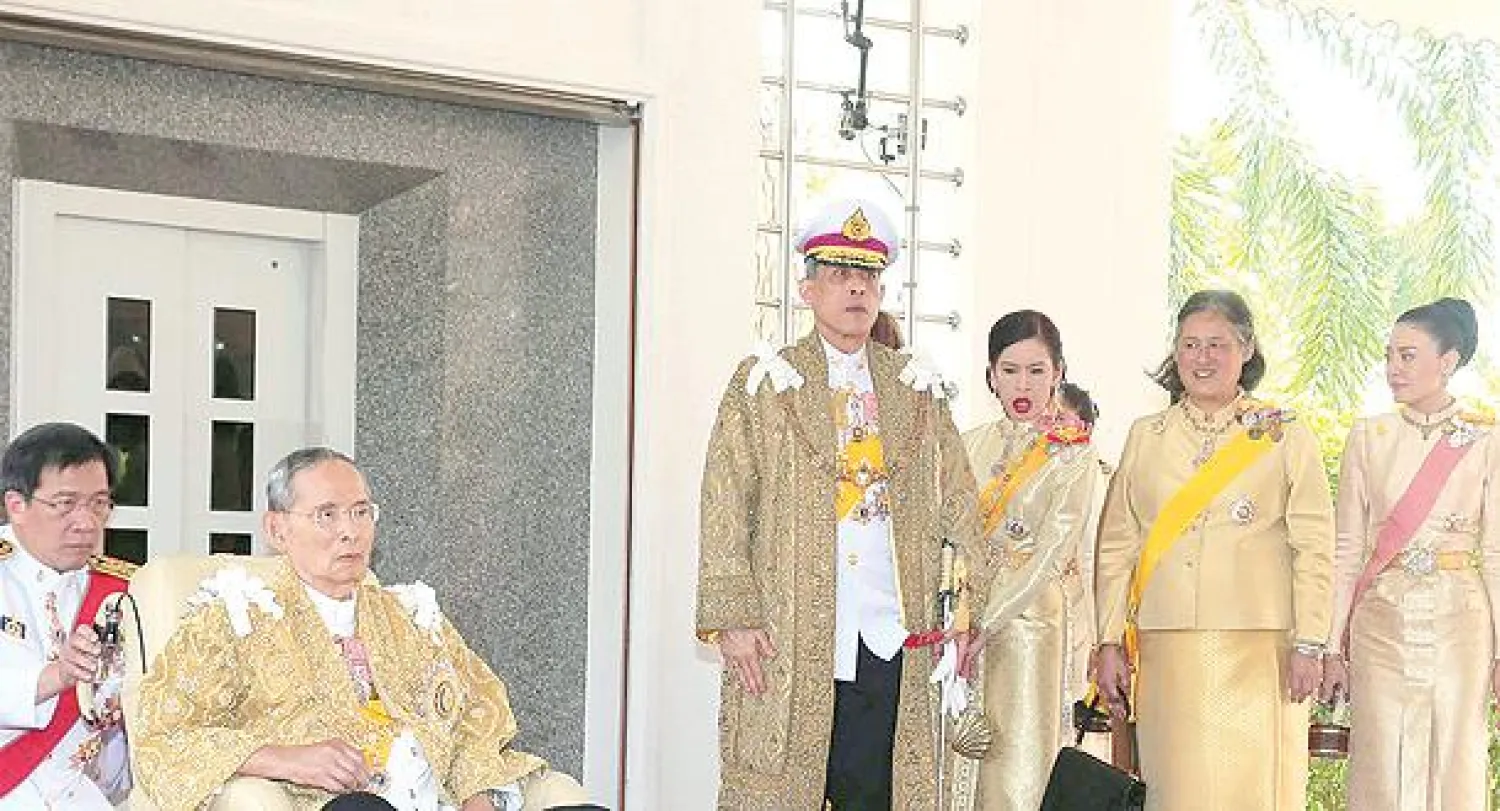 الملك أدولياديج يجلس على كرسي متحرك إلى جانب أفراد عائلته، وهم (من اليسار إلى اليمين) ابنه ولي العهد ماها فاجيرالونغورن، والأميرة شولابهورن، والأميرة ماها شكري سيريندهورن، وقرينة الملك الأميرة سريراسمي، خلال ظهوره العام بمناسبة عيد ميلاده في القصر الملكي أمس (إ.ب.أ)