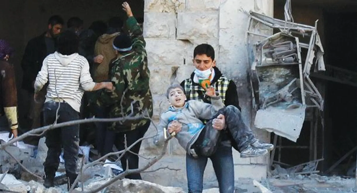 سوري يحمل صبيا انتشل من تحت ركام منزل بعد غارة جوية شنتها القوات الموالية للرئيس السوري بشار الأسد في مدينة حلب أمس (رويترز)
