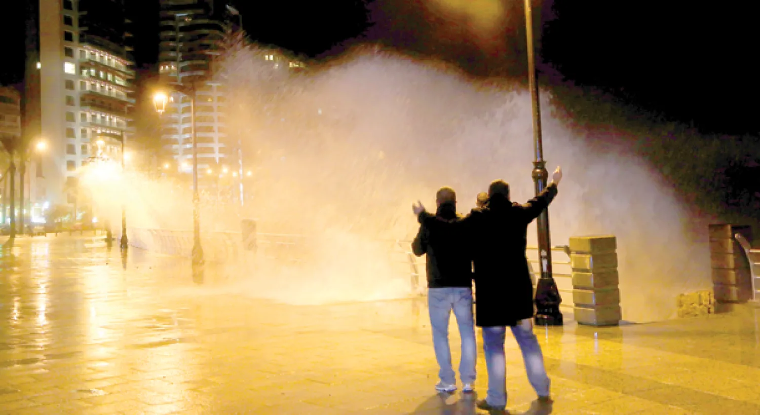 لبنانيون يراقبون الأمواج العالية وهي تضرب الكورنيش في بيروت أمس (أ.ب)