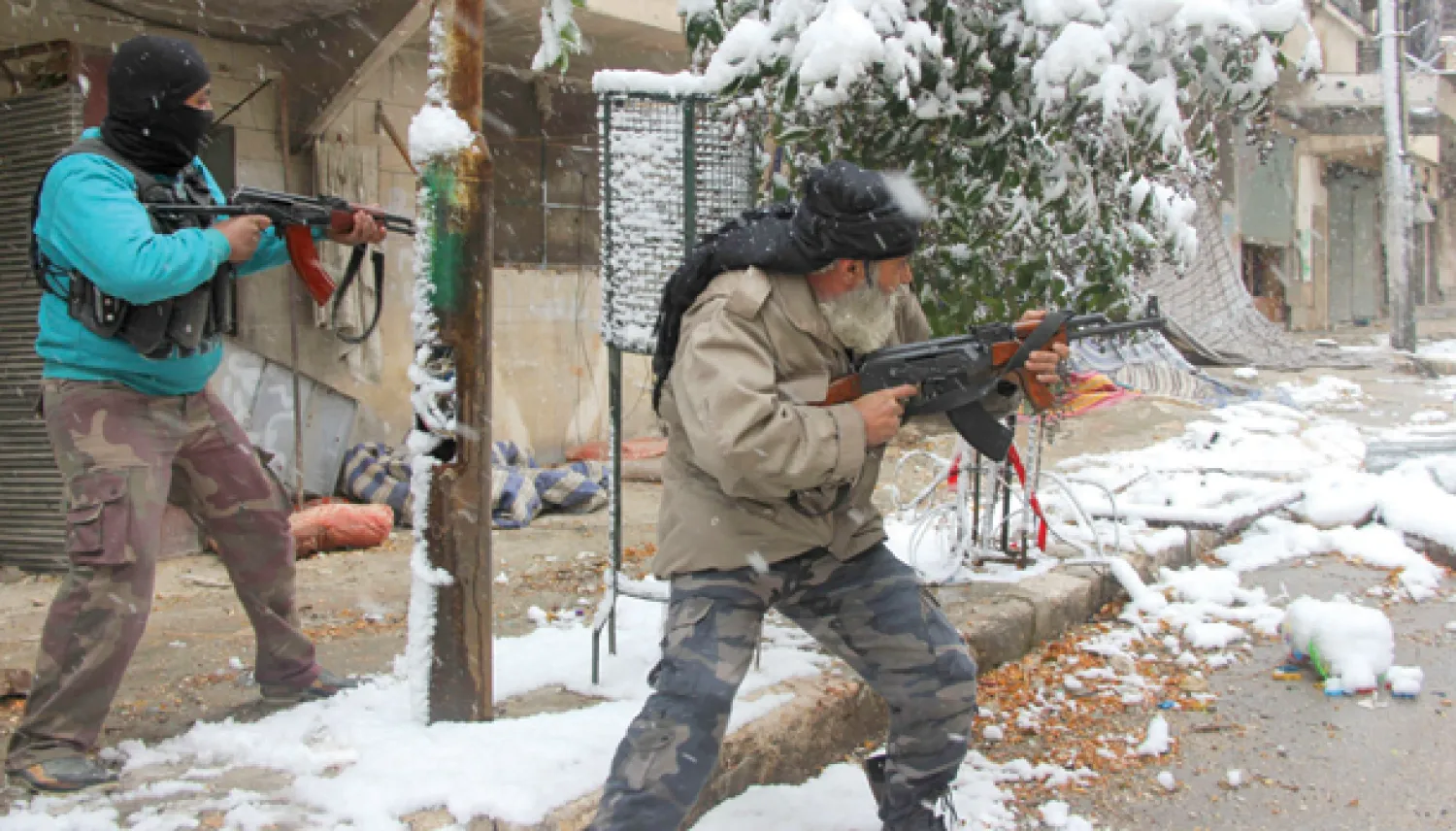مقاتلان من المعارضة السورية المسلحة يطلقان النار باتجاه موالين للنظام في حي صلاح الدين في حلب أمس (أ.ف.ب)