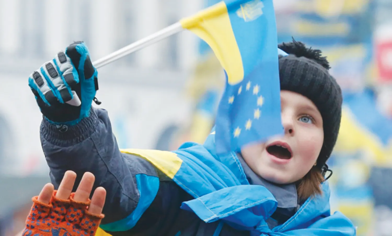 متظاهر أوكراني من مؤيدي الانضمام إلى أوروبا يحمل طفله فوق كتفيه الذي أمسك بيده علم بلاده في ميدان الاستقلال وسط العاصمة كييف أمس (رويترز)