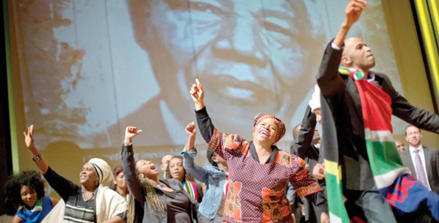 أعضاء من الجالية الجنوب أفريقية في مدينة أتلانتا الأميركية يغنون أمام صورة لمانديلا خلال حفل لنعيه في 12 من الشهر الحالي (أ.ب)