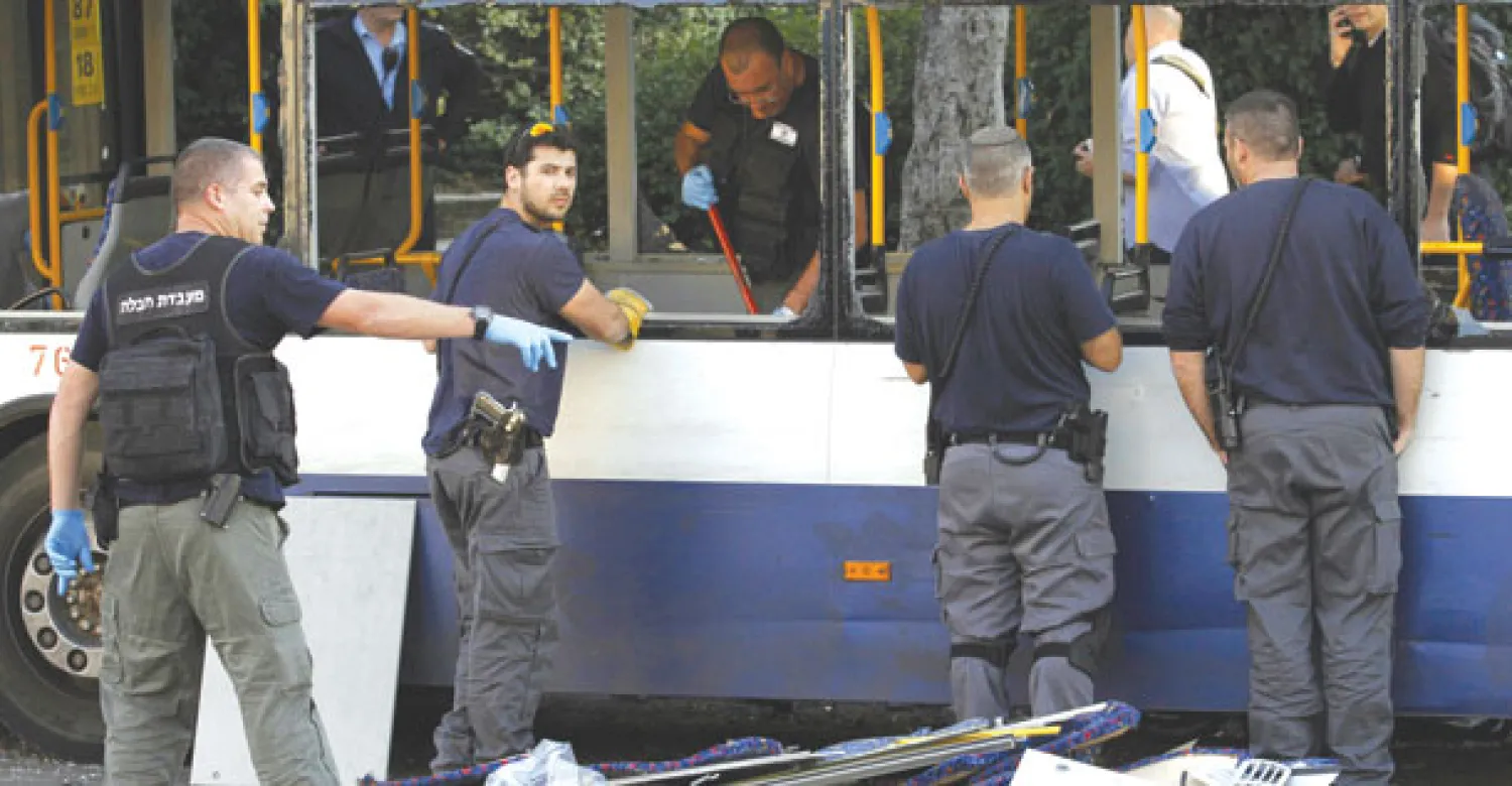 عناصر شرطة إسرائيليون يعاينون حافلة تعرضت لأضرار بعد انفجار قنبلة بداخلها في ضواحي تل أبيب دون إصابات أمس (أ.ب)