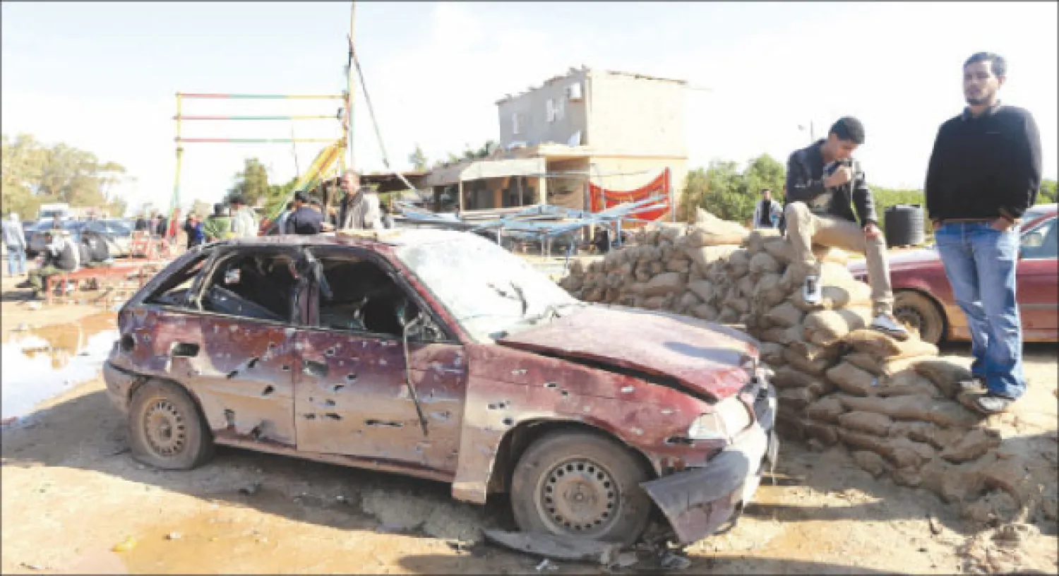 ليبيان يعاينان سيارة تم تدميرها في انفجار انتحاري ببنغازي أمس (رويترز)