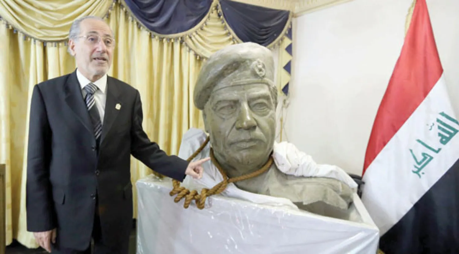 مستشار الأمن القومي العراقي السابق موفق الربيعي بجوار تمثال لصدام حسين التف حول رقبته الحبل الذي شنق به قبل سبع سنوات (أ.ف.ب)