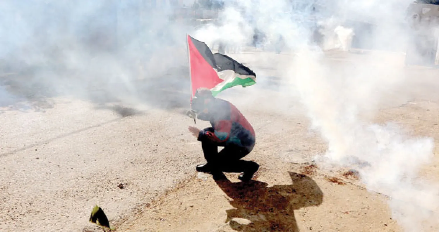فلسطيني وسط قنابل مسيلة للدموع خلال احتجاج ضد المستوطنات قرب نابلس أمس (إ.ب.أ)