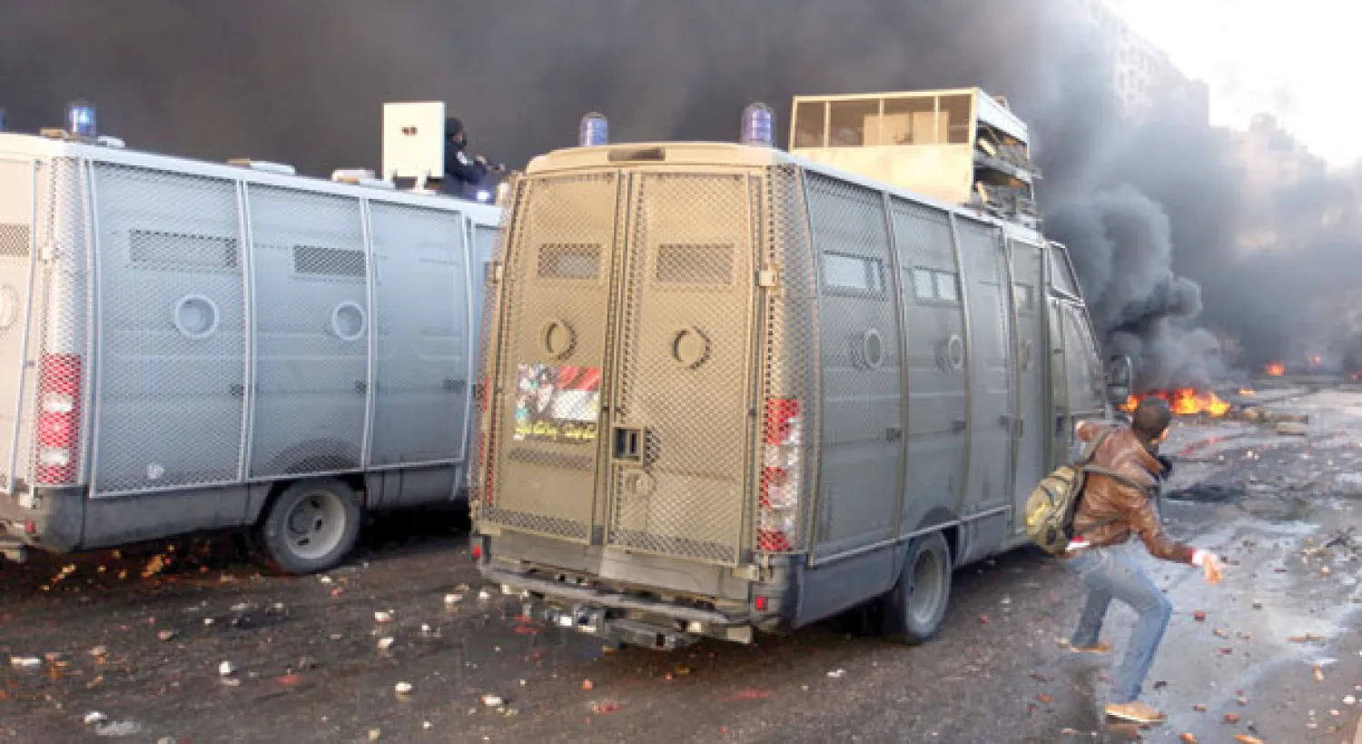 سيارات قوات الأمن المركزي ومكافحة الشغب المصري تتقدم بينما تتصاعد الأدخنة والنيران التي أشعلها متظاهرون ينتمون إلى جماعة الإخوان في أحد شوارع القاهرة أمس (إ.ب.أ)