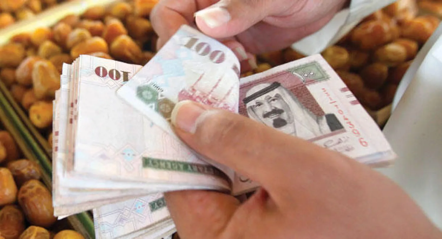 سعودي يحصي النقود في سوق للتمور في بريدة (رويترز)