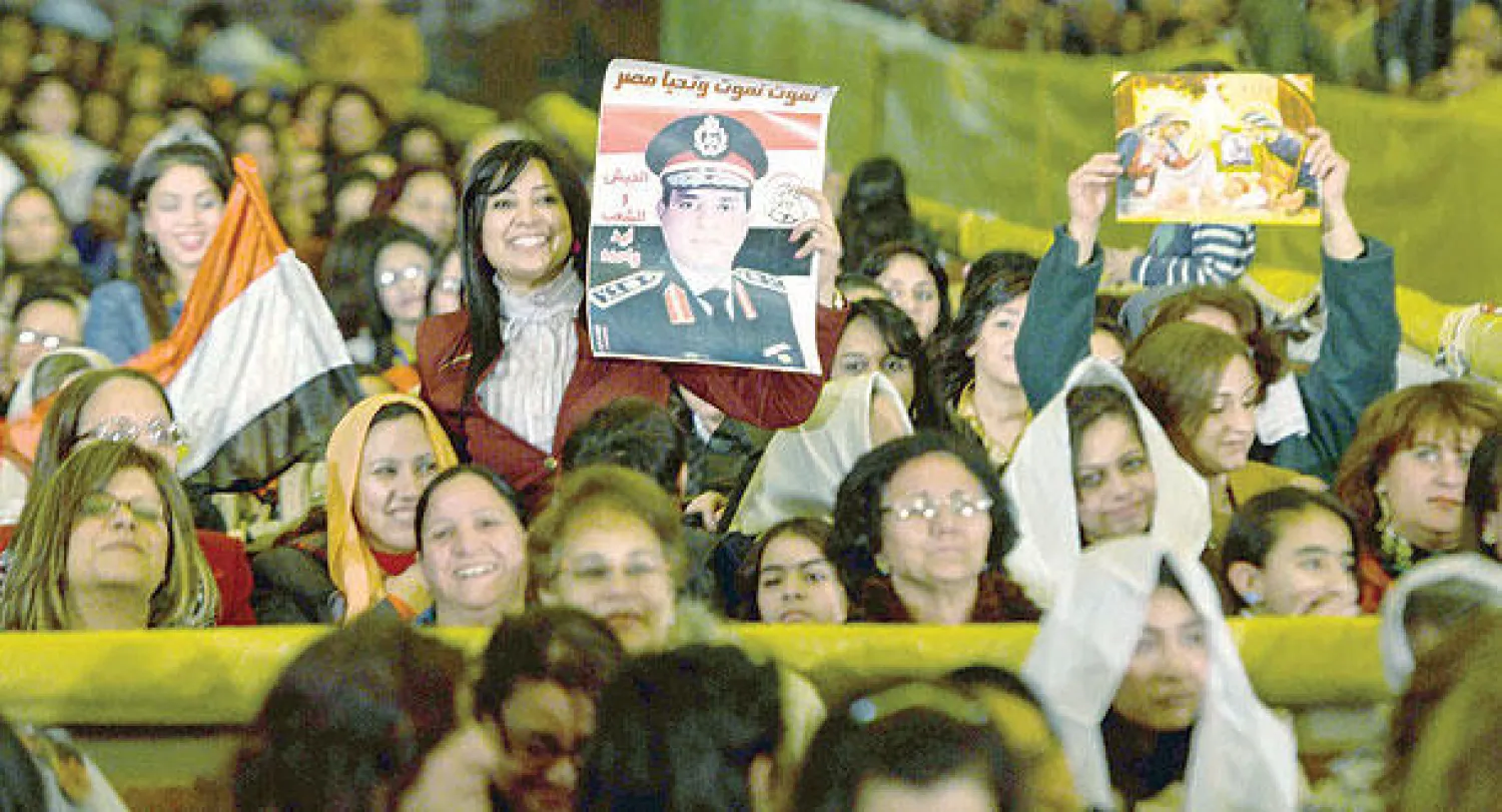 مسيحيات يرفعن أيقونات دينية وأعلاما مصرية وصورا للفريق أول عبد الفتاح السيسي خلال الاحتفال بأعياد الميلاد في الكاتدرائية المرقسية وسط القاهرة الليلة قبل الماضية (أ.ف.ب)