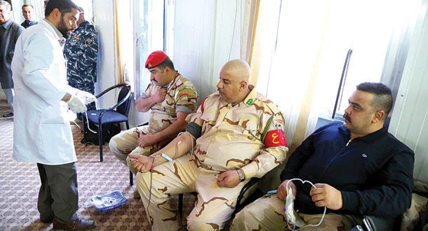 جنود عراقيون يتبرعون بالدم لجرحى العمليات العسكرية في الأنبار أمس (أ.ب)
