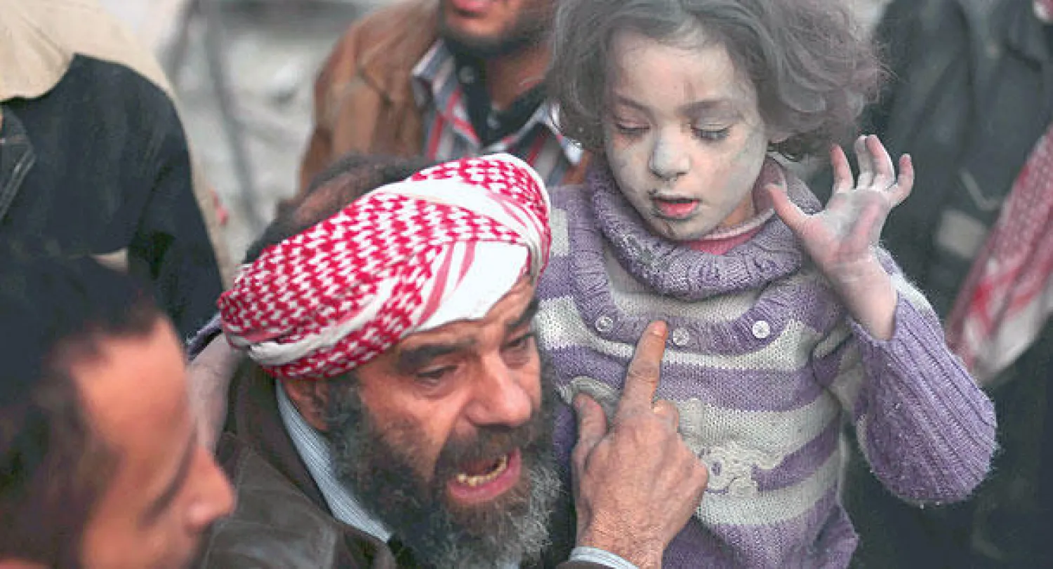 سوري يحمل طفلة انتشلها من بين الأنقاض بعد غارة جوية شنها النظام السوري على منطقة دوما في دمشق أمس (رويترز)