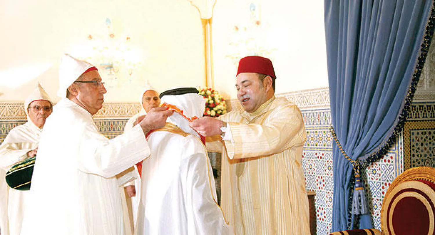 الملك محمد السادس لدى توشيحه السفير السعودي بوسام رفيع في القصر الملكي بمراكش أمس (ماب)