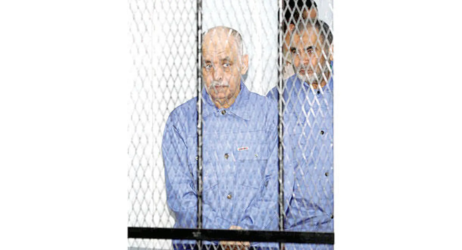 البغدادي المحمودي آخر رئيس وزراء في عهد معمر القذافي أثناء محاكمته بتهمتي القتل والفساد في طرابلس أمس (أ.ف.ب)