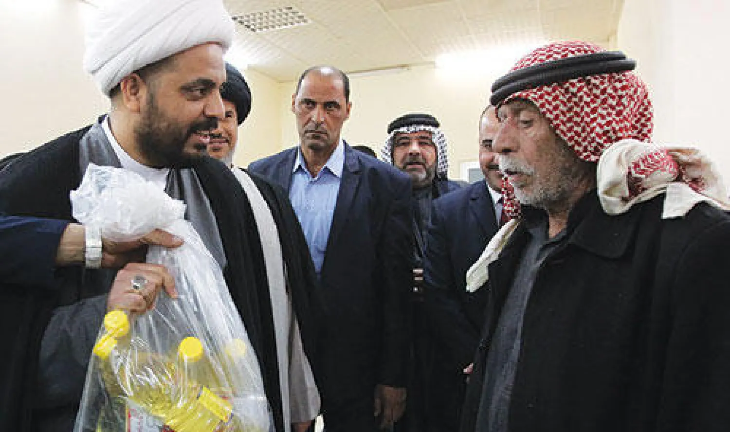 لاجئ عراقي من أهالي الفلوجة مع عائلته إلى كربلاء يتسلم مساعدات غذائية من عصائب أهل الحق أمس (أ.ف.ب)