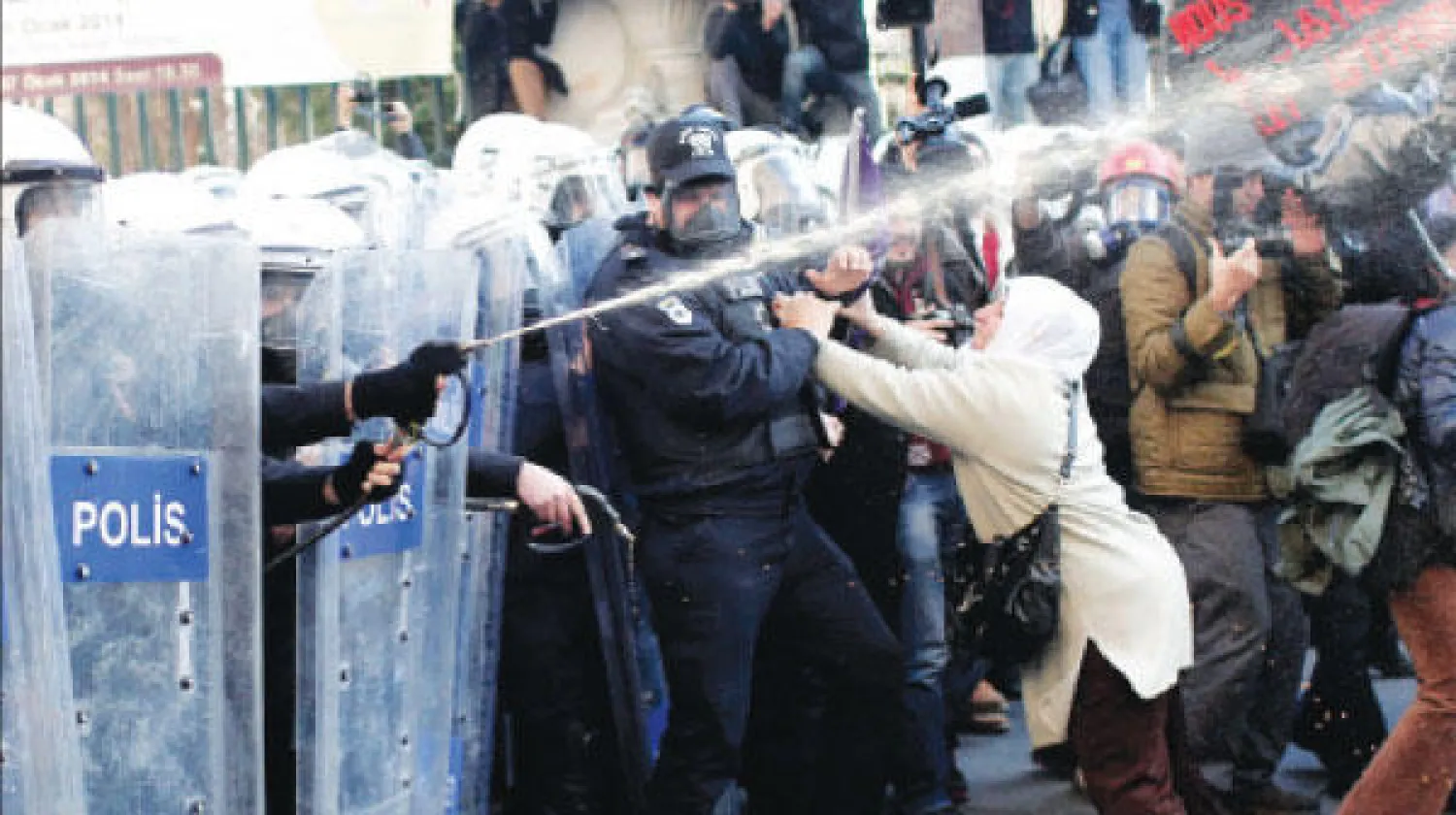 ناشطة كردية تحاول إبعاد شرطي تركي خلال مواجهات مع قوات مكافحة الشغب في إسطنبول أمس (أ.ف.ب)