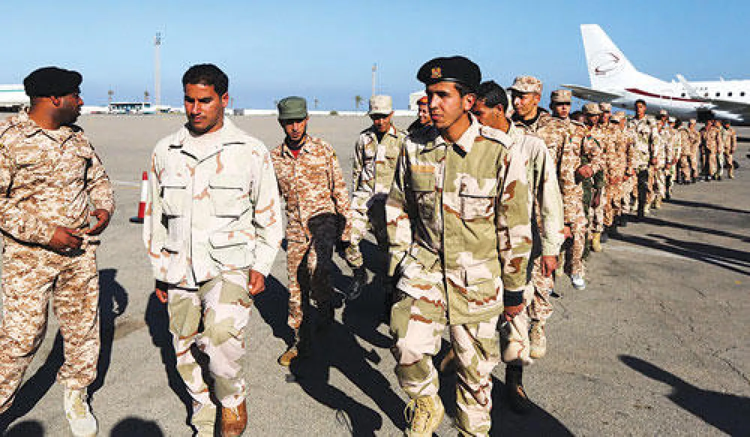 عدد من الثوار الليبين بعد انضمامهم إلى الجيش في طريقهم لركوب الطائرة للتوجه إلى ايطاليا لتلقي التدريب العسكري (أ.ف.ب)