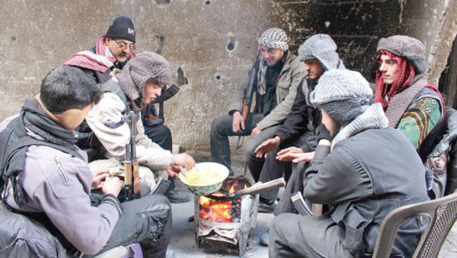 عناصر من الجيش السوري الحر يستدفئون ويطهون طعامهم على الحطب في إحدى قرى غوطة دمشق أمس (رويترز)
