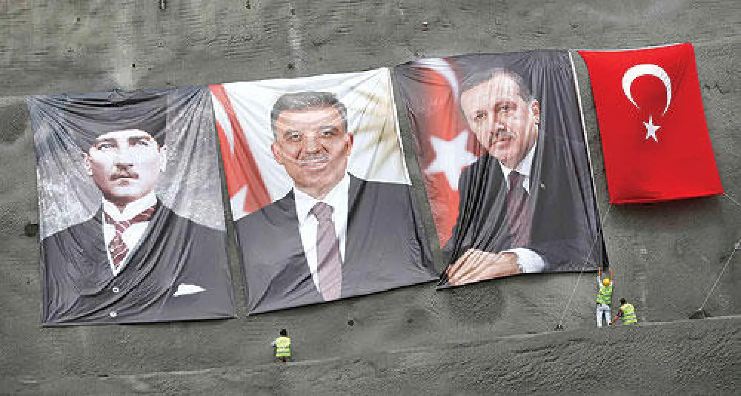 عمال اتراك يرفعون صور مؤسس تركيا اتاتورك وإردوغان وغل في اسطنبول أمس (رويترز)