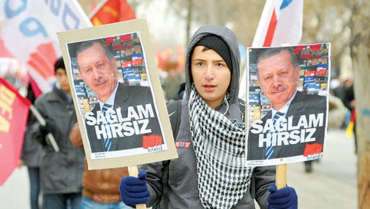 تركي يرفع صورتين لرئيس الوزراء التركي إردوغان أمس في مظاهرة احتجاجا على ملفات الفساد التي تشهدها الحكومة (رويترز)