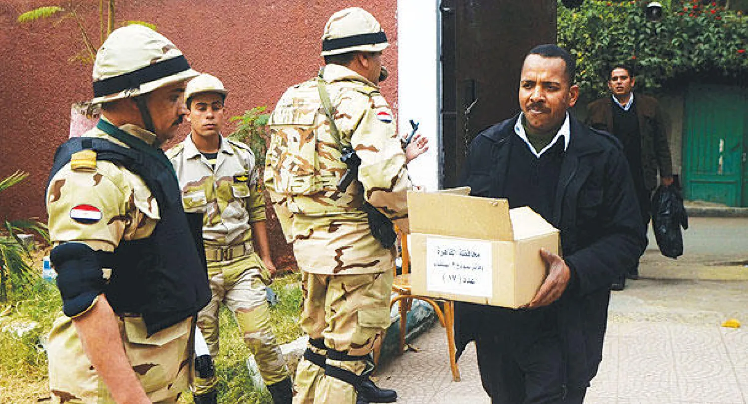 عامل تابع للجنة العليا للانتخابات يحمل صندوق أوراق الاقتراع قبيل ساعات من انطلاق عملية الاستفتاء على الدستور المصري الجديد (أ.ف.ب)