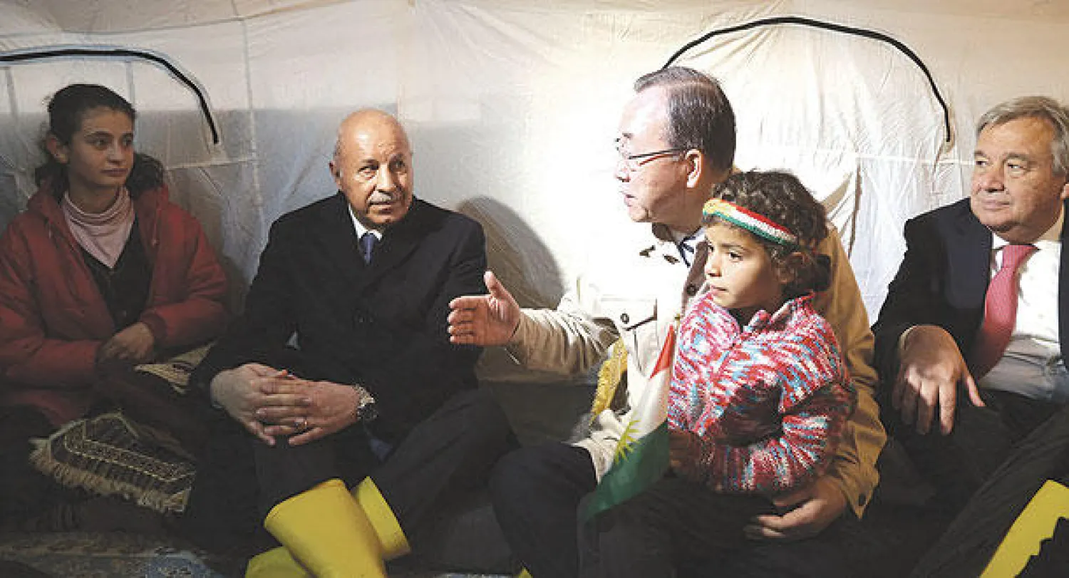 الأمين العام للأمم المتحدة بان كي مون يتحدث إلى أفراد أسرة خلال زيارته لمخيم  للاجئين الأكراد السوريين قرب أربيل أمس (رويترز)