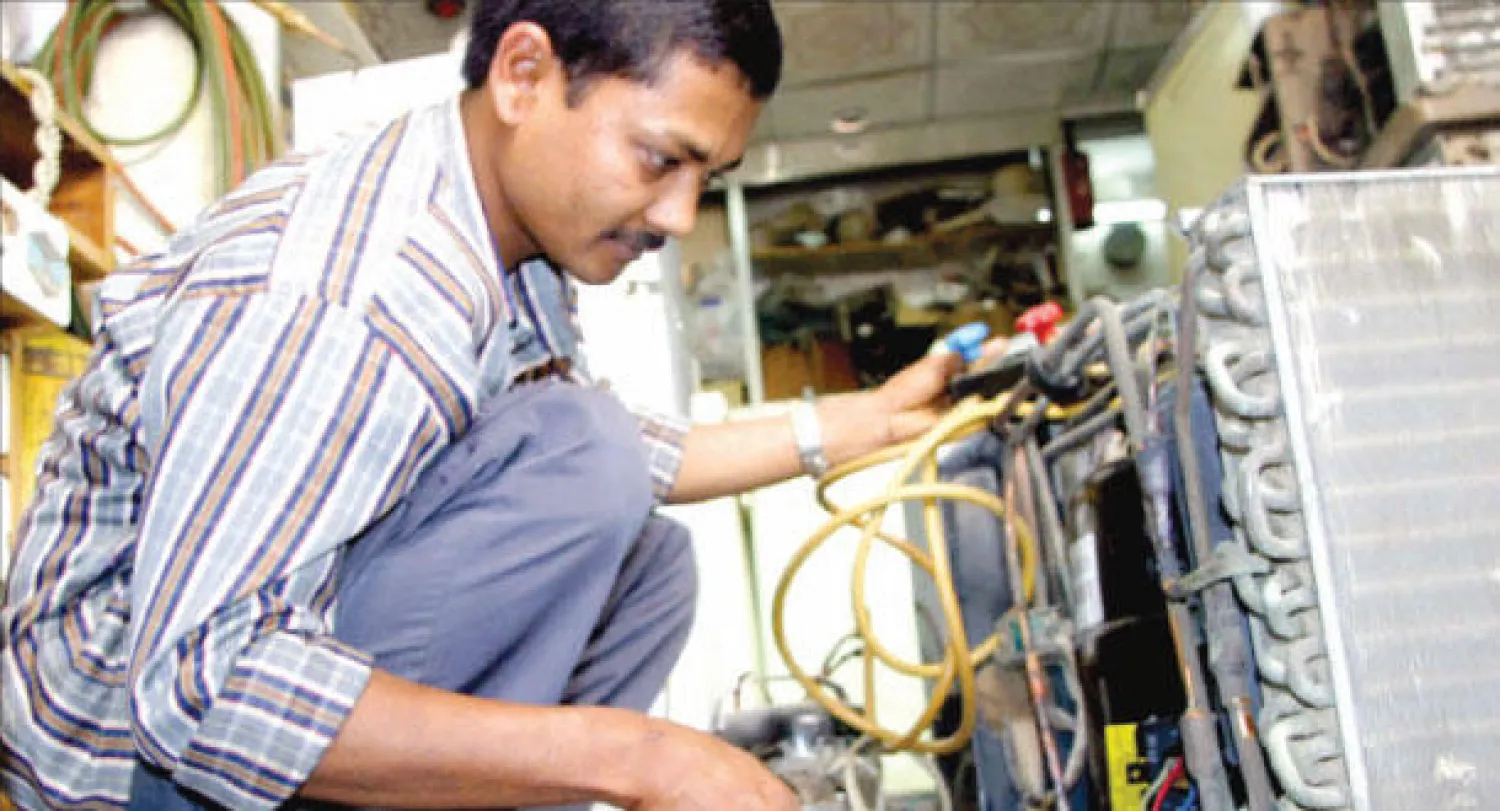 عامل صيانة يصلح أحد أجهزة التكييف ({الشرق الأوسط})