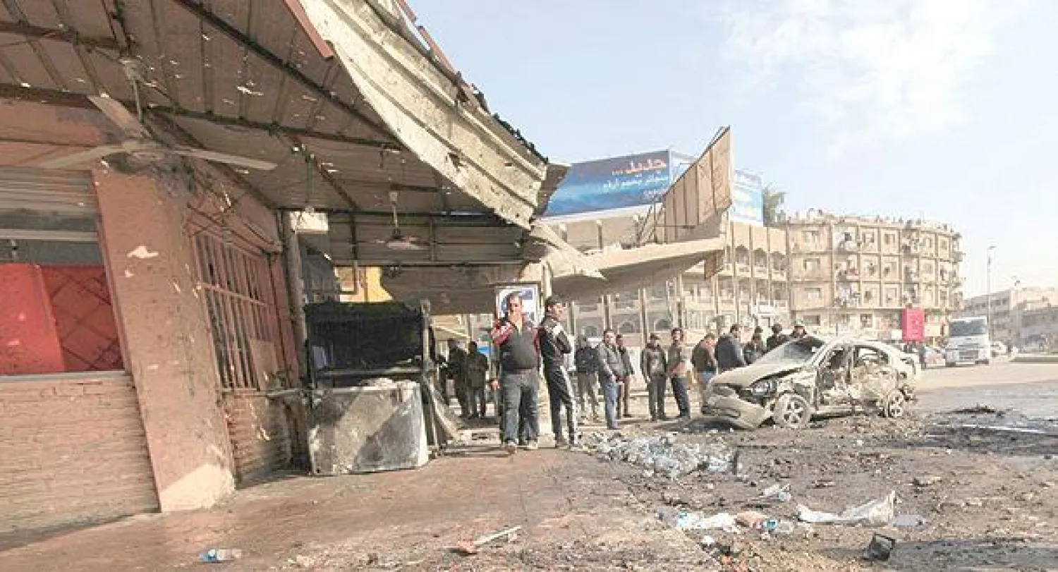 عراقيون يعاينون حطام سيارة في موقع انفجار ببغداد أمس (رويترز)