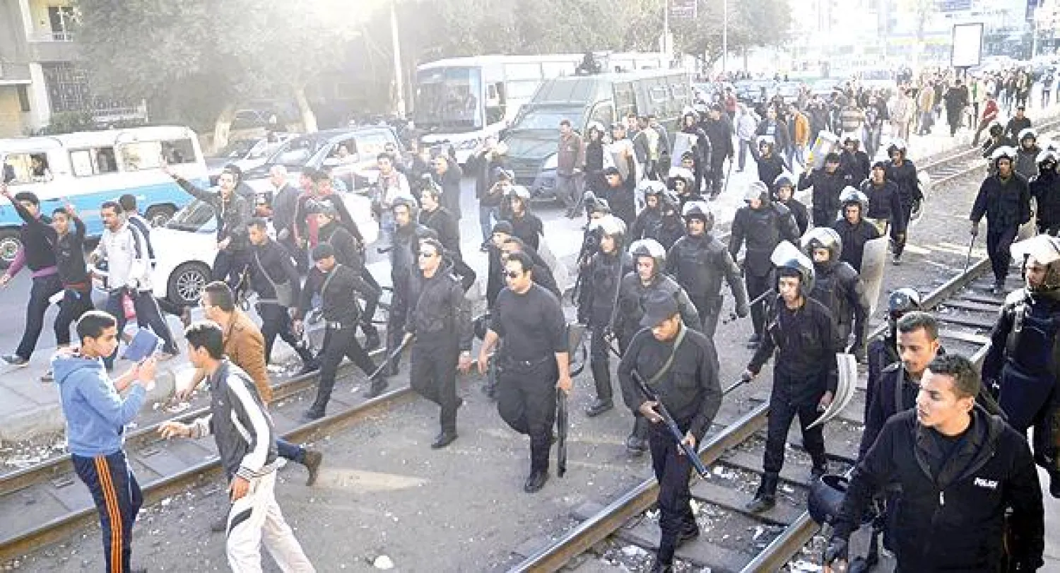 مواطنون يتقدمون مع عناصر من الأمن عقب إخلاء ميدان روكسي شرق القاهرة أمس من مظاهرة للإخوان قامت بإشعال النار في أحد مراكز الشرطة (أ.ف.ب)