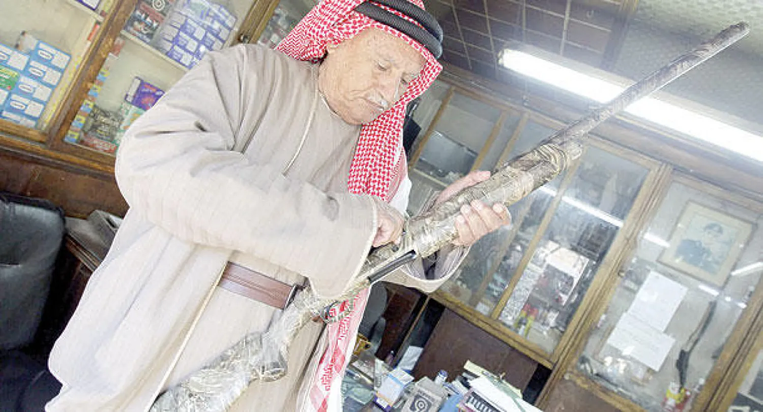 أردني يتفحص بندقية في محل لبيع الأسلحة النارية في العاصمة عمان (أ.ف.ب)