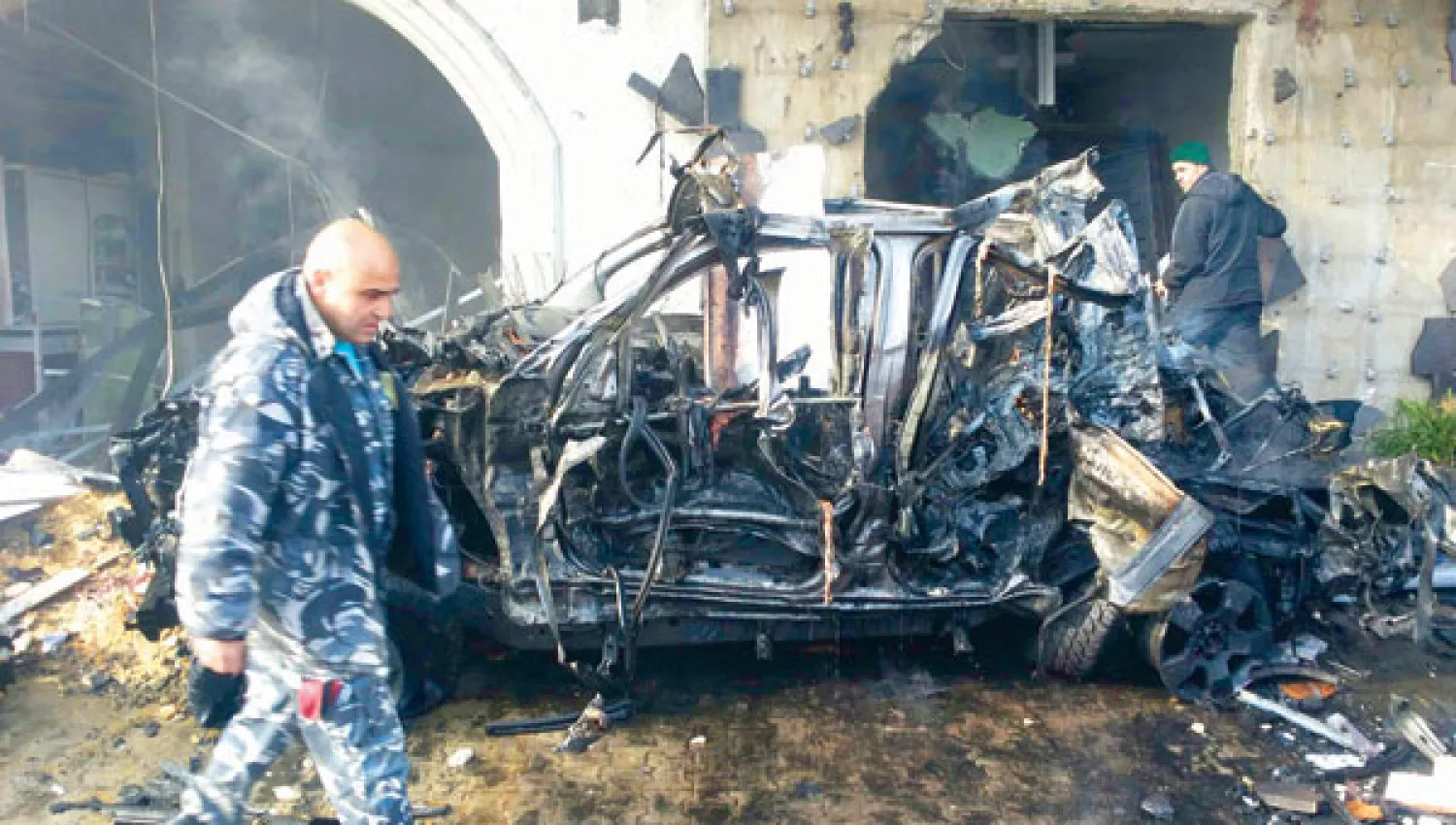 عنصر أمن يمر أمام سيارة تضررت بفعل الانفجار الذي وقع في مدينة الهرمل بشرق لبنان أمس (رويترز)