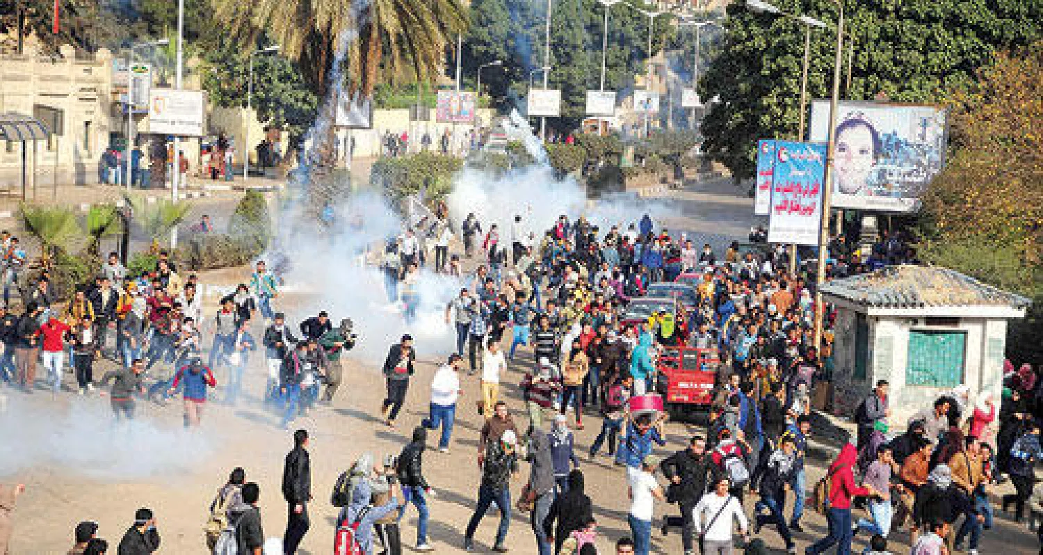 أنصار لجماعة الإخوان يهربون من قنابل الغاز التي أطلقتها قوات الأمن ردا على تعديهم على بعض المنشآت والسيارات في محيط جامعة القاهرة أمس (أ.ب)