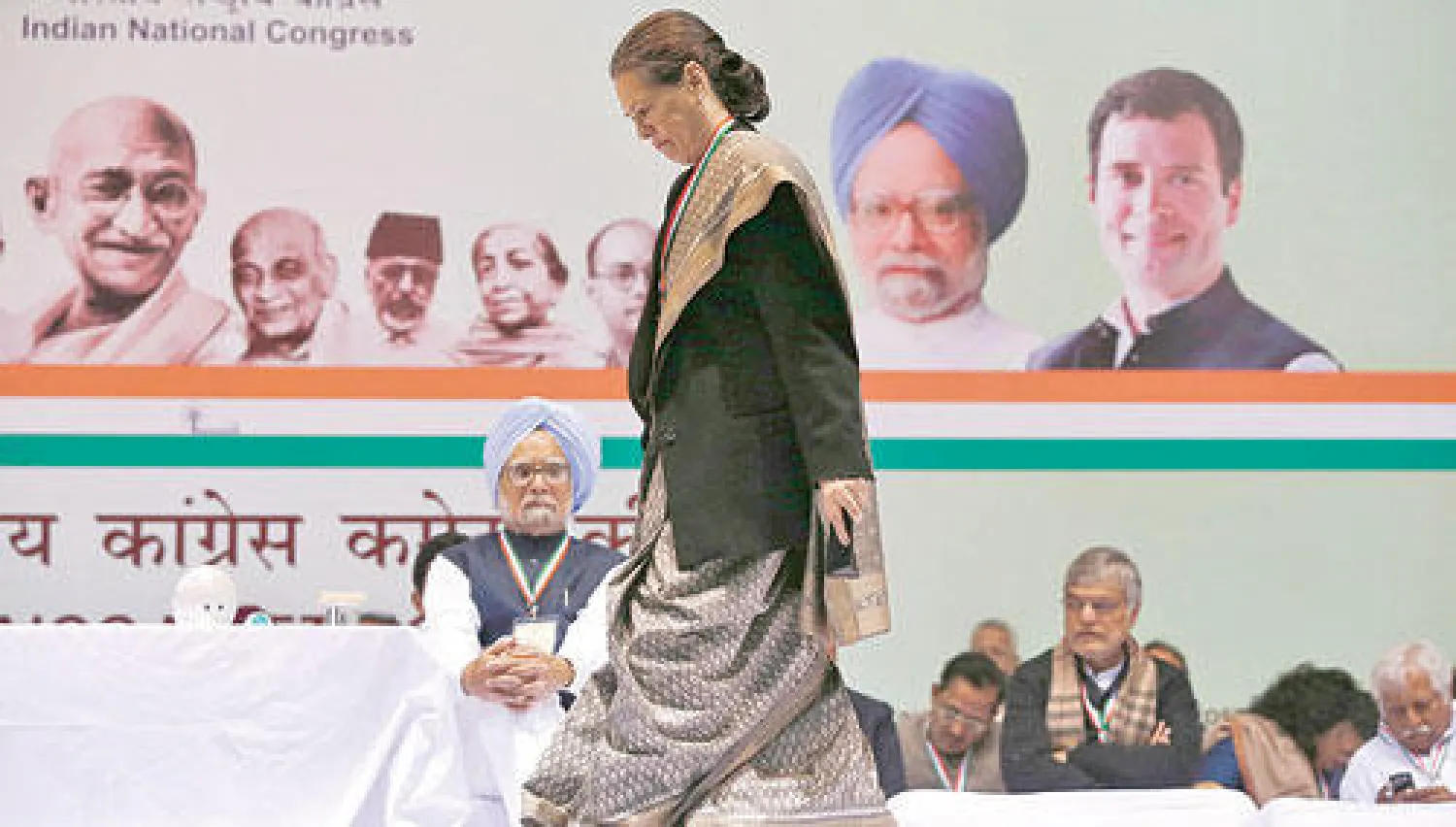 سونيا غاندي تسير أمام مانموهان سينغ لإلقاء كلمتها أمس فيما تبدو صورة لنجلها راؤول (أعلى يمين) ضمن صور قادة آخرين للبلاد في نيودلهي أمس (رويترز)