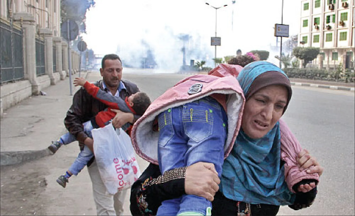 عائلة تحاول الفرار من قنابل الغاز المسيل للدموع في أحد مواقع الاشتباكات بين أنصار «الإخوان» وقوات الأمن في القاهرة أمس (أ.ب)