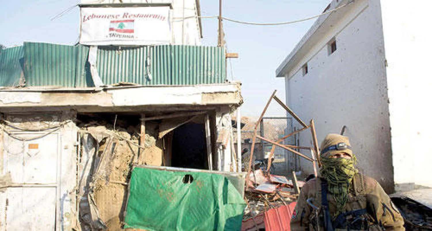 عنصر من القوات الأفغانية الخاصة يراقب الوضع أمام المطعم اللبناني الذي استهدفه هجوم لحركة طالبان في كابل أمس (أ.ف.ب)