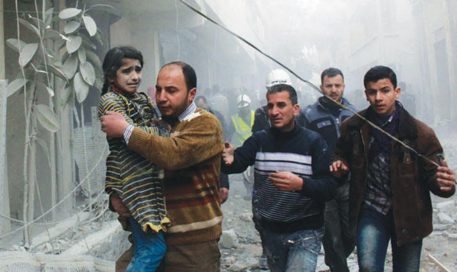 سوري يحمل طفلة أنقذت من أنقاض منزل دمره القصف الجوي من قبل قوات النظام في منطقة الميسر بحلب أمس (رويترز)