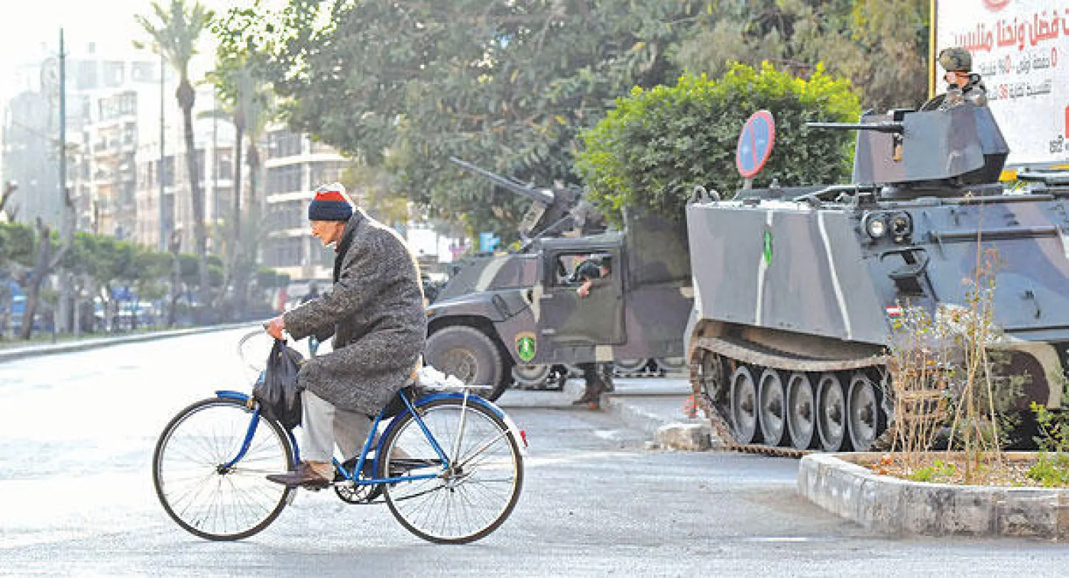 لبناني على ظهر دراجته يمر بنقطة تفتيش أقامها الجيش عند المدخل الشمالي لمدينة طرابلس أمس (أ.ف.ب)