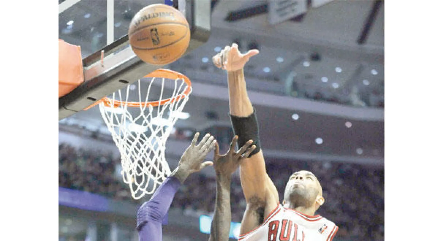 جيبسون لاعب شيكاغو بولز رقم 22 يسجل في حلقة ليكرز رغم مداخلة من هاريس لاعب الأخير (أ.ب)