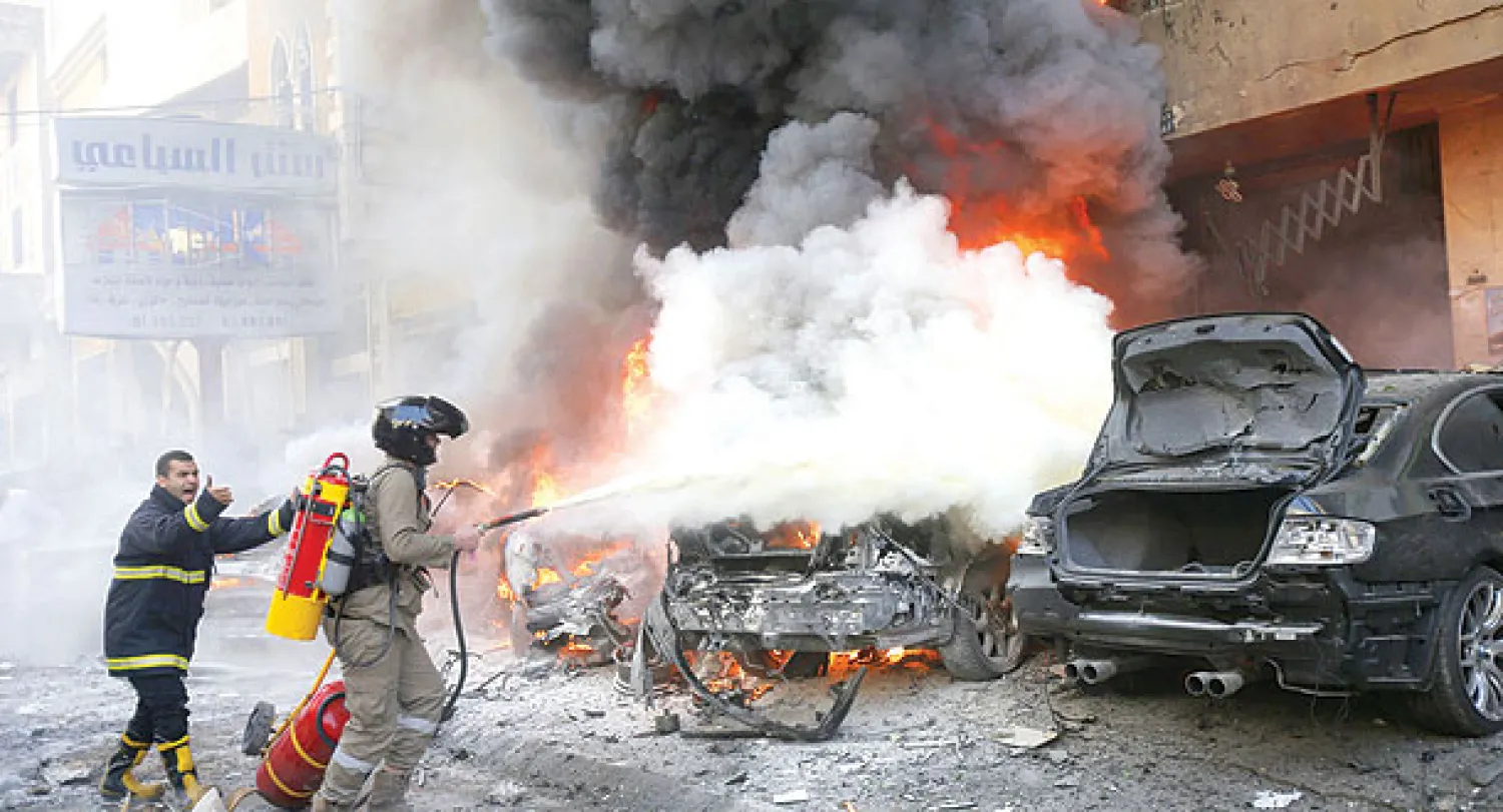 عمال إطفاء يخمدون النيران المشتعلة في سيارات إثر التفجير  الذي استهدف حارة حريك بالضاحية الجنوبية لبيروت معقل حزب الله أمس (أ.ف.ب)