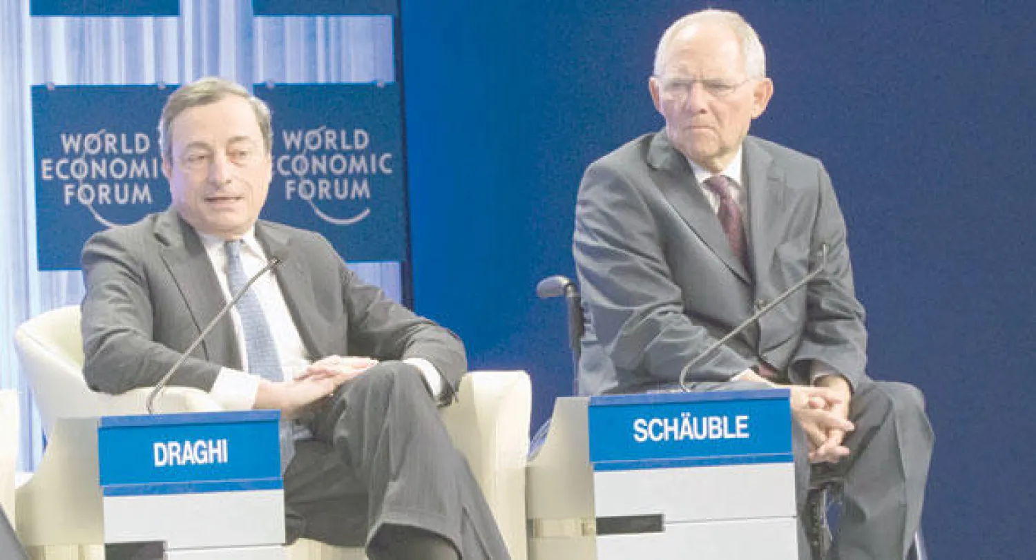 ماريو دراغي رئيس البنك المركزي الأوروبي ووزير المالية الألماني ولفغانغ شويبله خلال جلسة في منتدى دافوس الاقتصادي أمس (أ.ب)