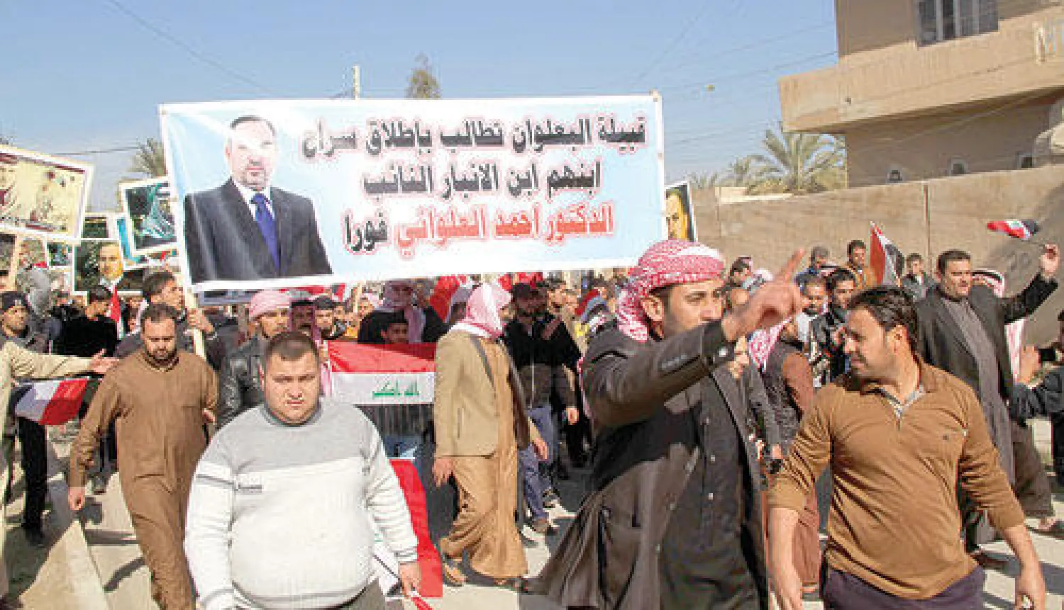 عراقيون يحملون لافتة عليها صورة النائب المعتقل أحمد العلواني تطالب بإطلاق سراحه خلال مسيرة في الرمادي أمس (أ.ف.ب)
