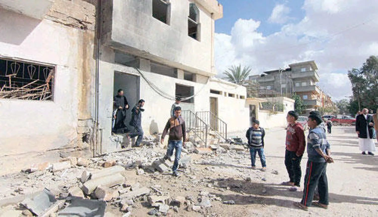 ليبيون يقفون قرب مسجد طالته أضرار إثر انفجار وقع في بنغازي أمس (رويترز)