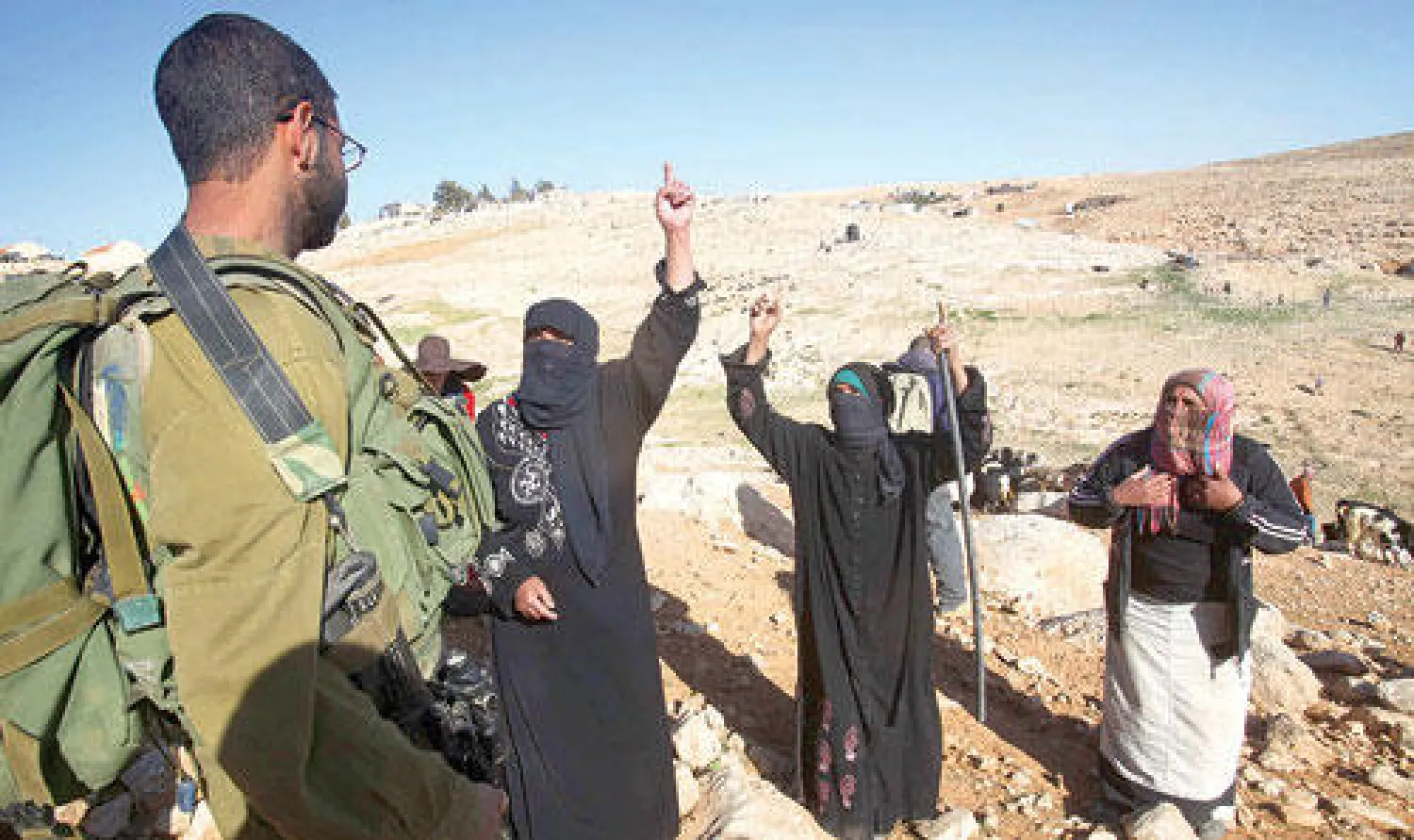 راعيتا غنم فلسطينيتان تشكوان لجندي اسرائيلي اعتداءات مستوطنين قرب قرية أم الخير في الخليل أمس (أ.ف.ب)