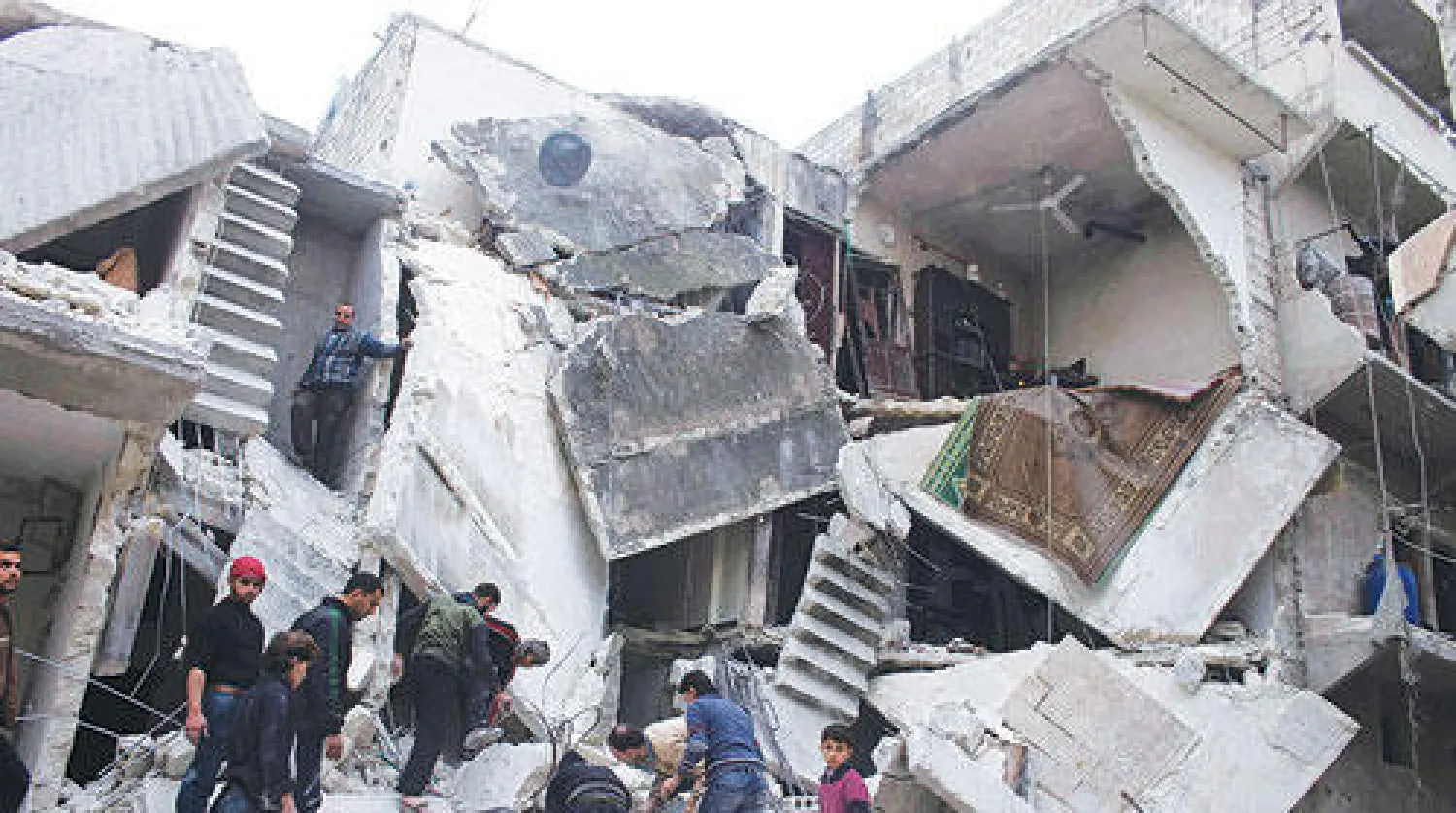 سوريون بين الانقاض بعد غارة جوية استهدفت حي صلاح الدين في مدينة حلب (رويترز)