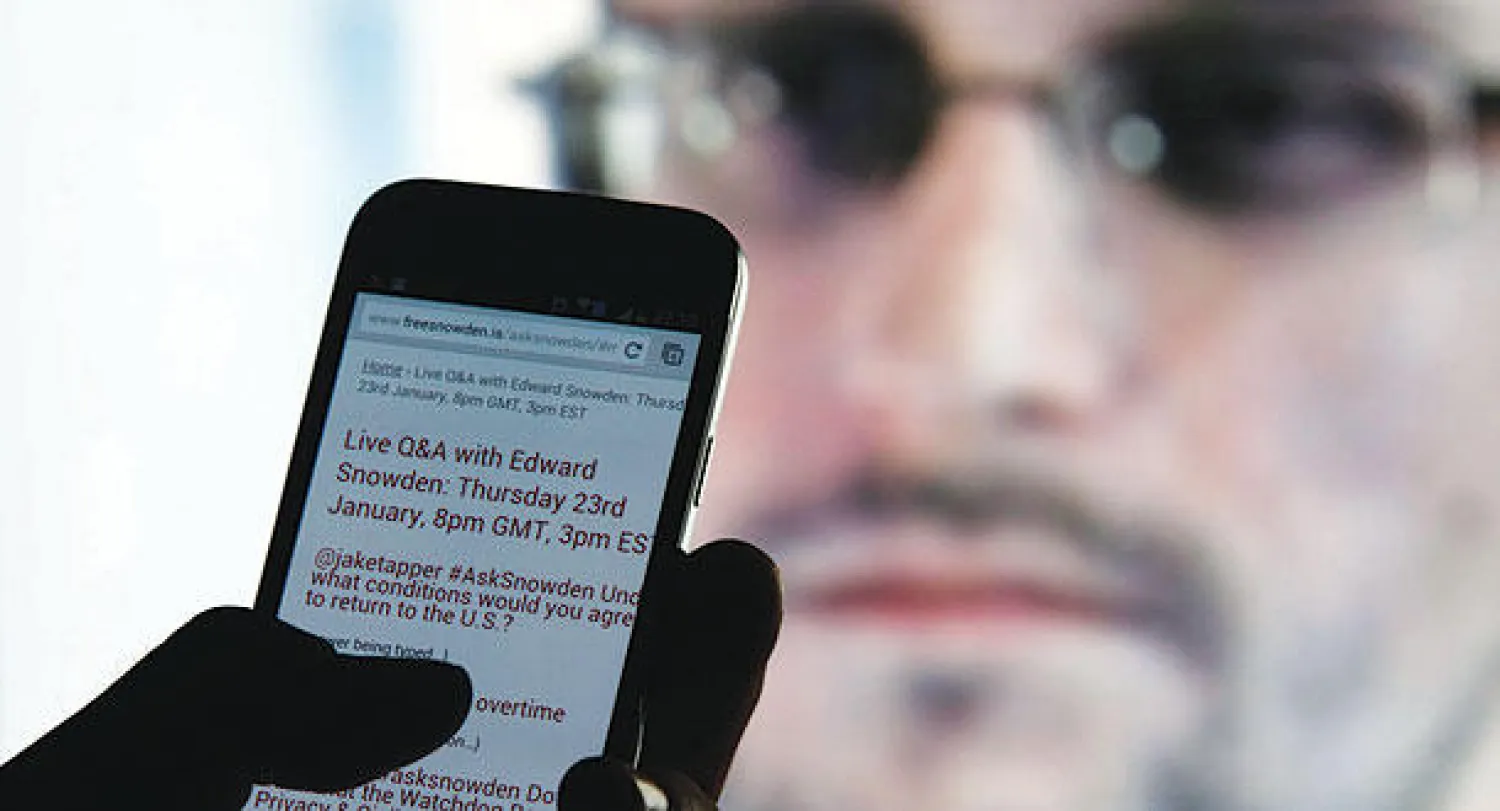 مواطن من سراييفو يقرأ أجوبة سنودن عبر «تويتر» في اللقاء التليفزيوني باستخدام شاشة هاتف جوال أمس (رويترز)
