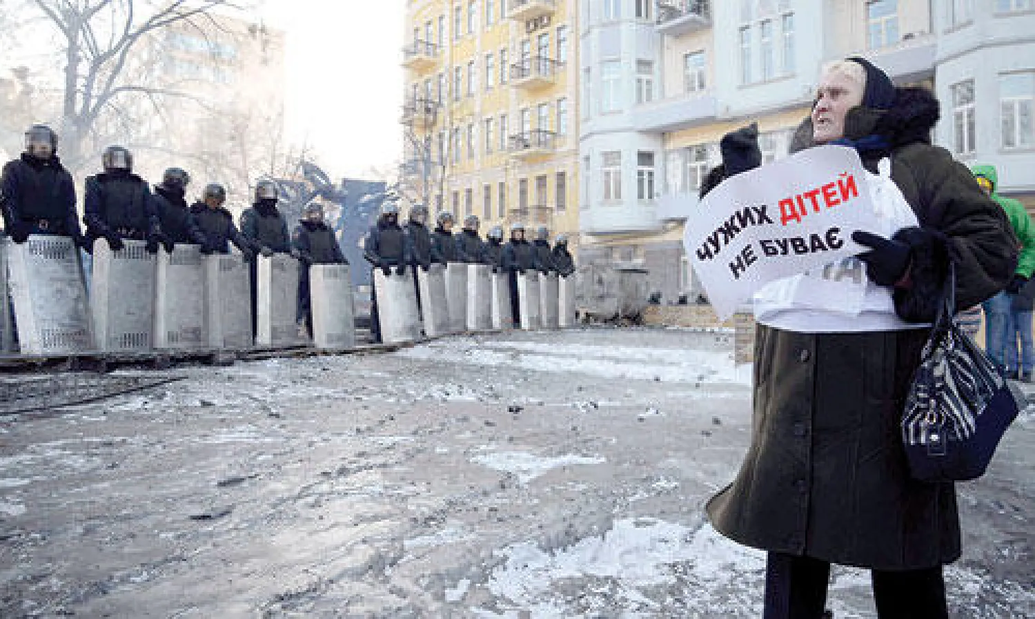 امرأة تردد شعارات مناهضة للحكومة أمام صف لقوات مكافحة الشغب في وسط كييف أمس (رويترز)