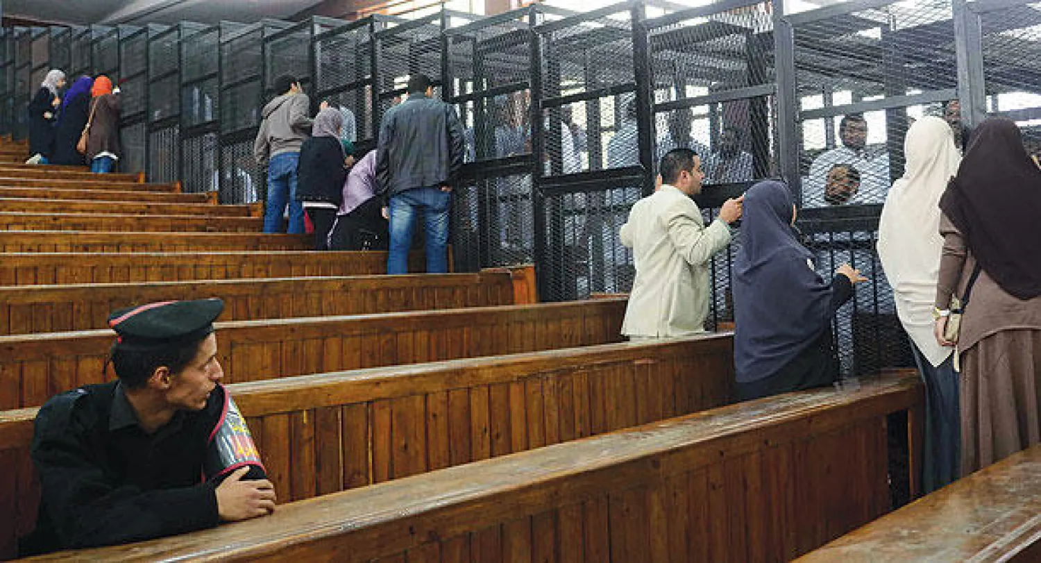 أقارب المتهمين من قيادات الإخوان يتحدثون إلى ذويهم قبيل بدء جلسة محاكمتهم أمس جنوب القاهرة (أ.ف.ب)