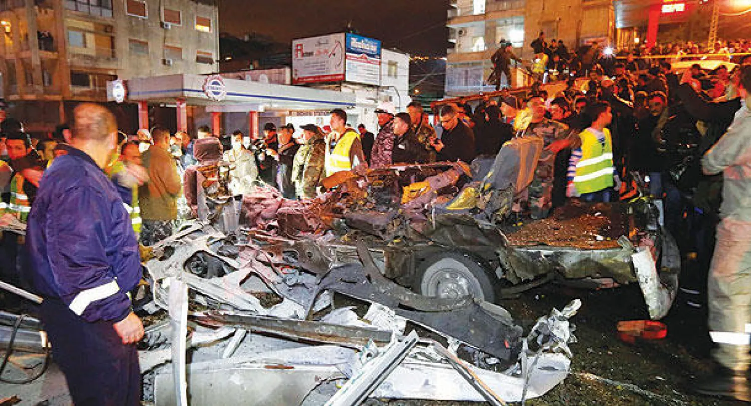 مواطنون ورجال أمن لبنانيون يعاينون السيارة التي فجرها الانتحاري أمس (رويترز)