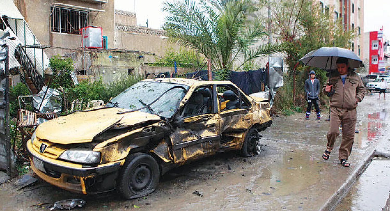 عراقيون في موقع انفجار سيارة مفخخة بمنطقة الحرية في بغداد أمس (أ.ب)