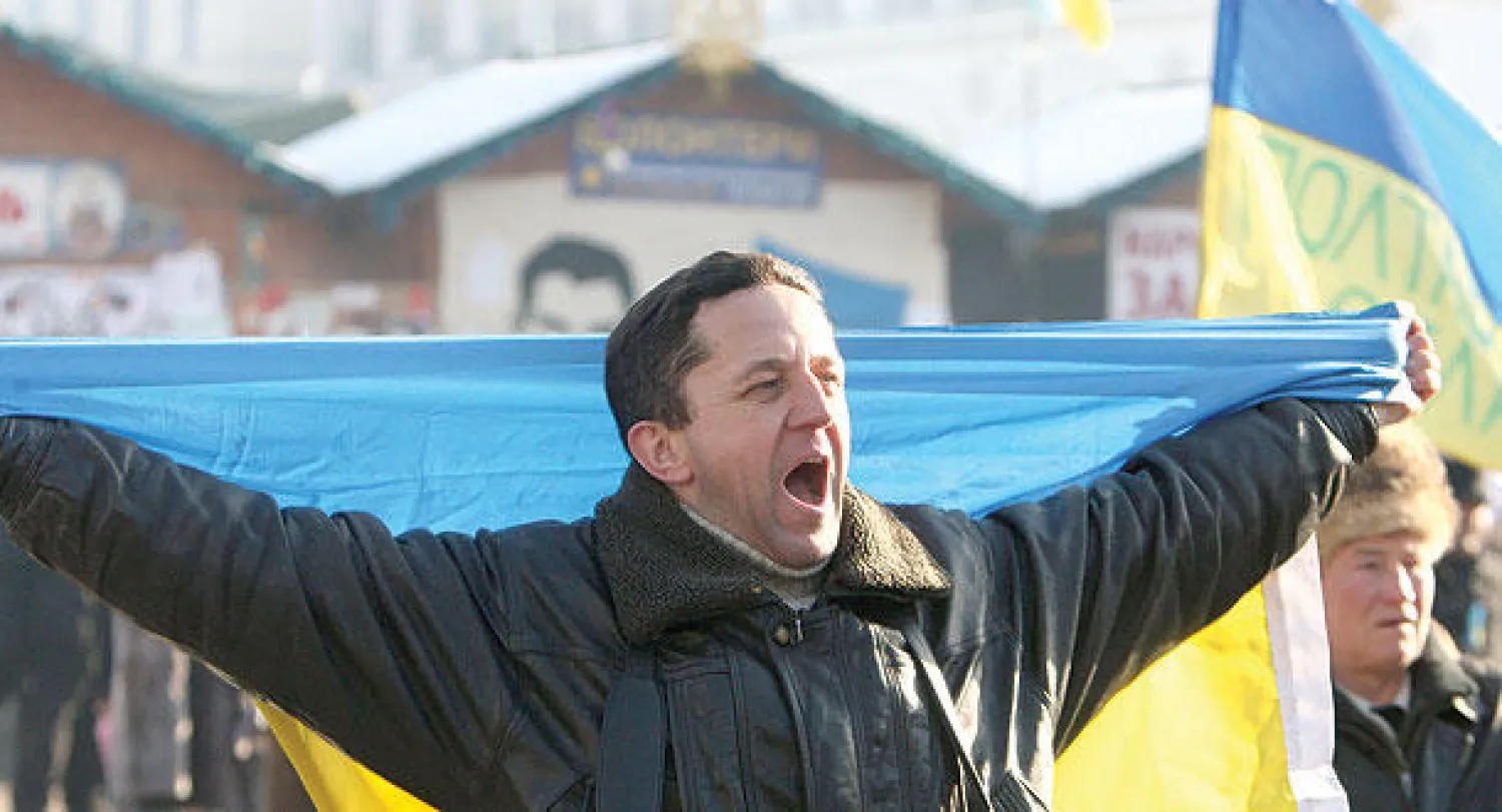 متظاهر يغني النشيد الوطني الأوكراني خلال تجمع للمحتجين في كييف أمس (إ.ب.أ)